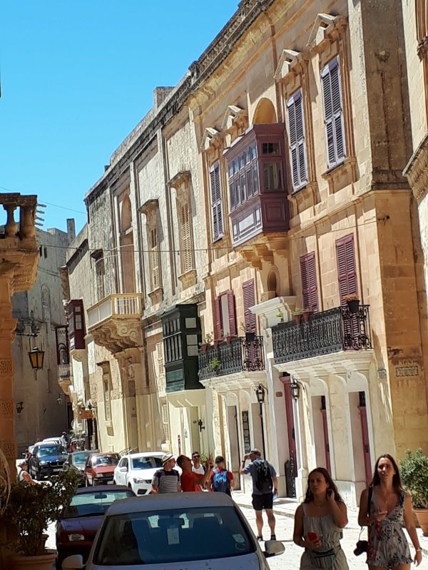 Een straat vol gevels met traditionele kleurrijke luiken en sierlijke balkons in Mdina, Malta