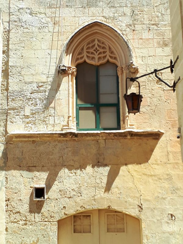 Een gotisch raam in een kalkstenen gevel, ergens in de binnenstad van Mdina, Malta
