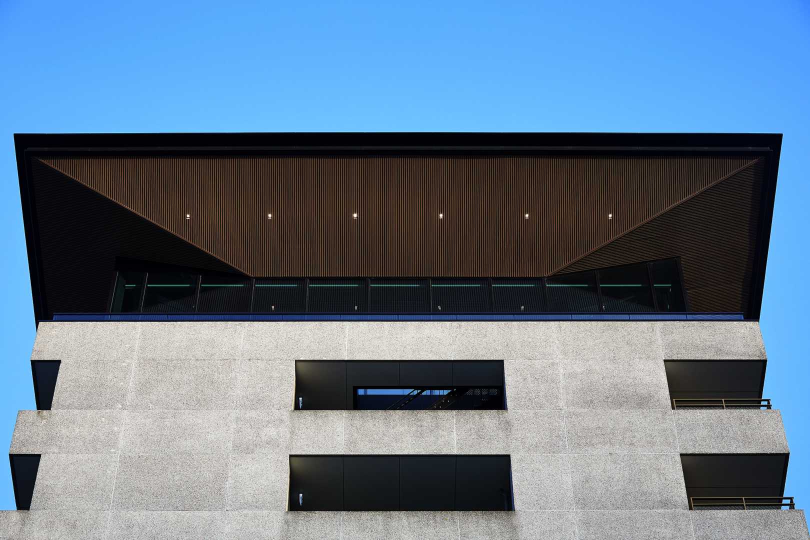 Buitenzijde: Luxalon® 30BD plafondsysteem Betonnen gevel en metalen dak